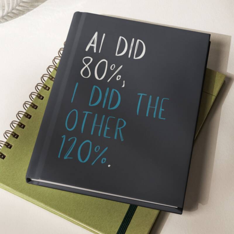 Black hadcover journal with large font in white and blue on top of a green spiral journal.