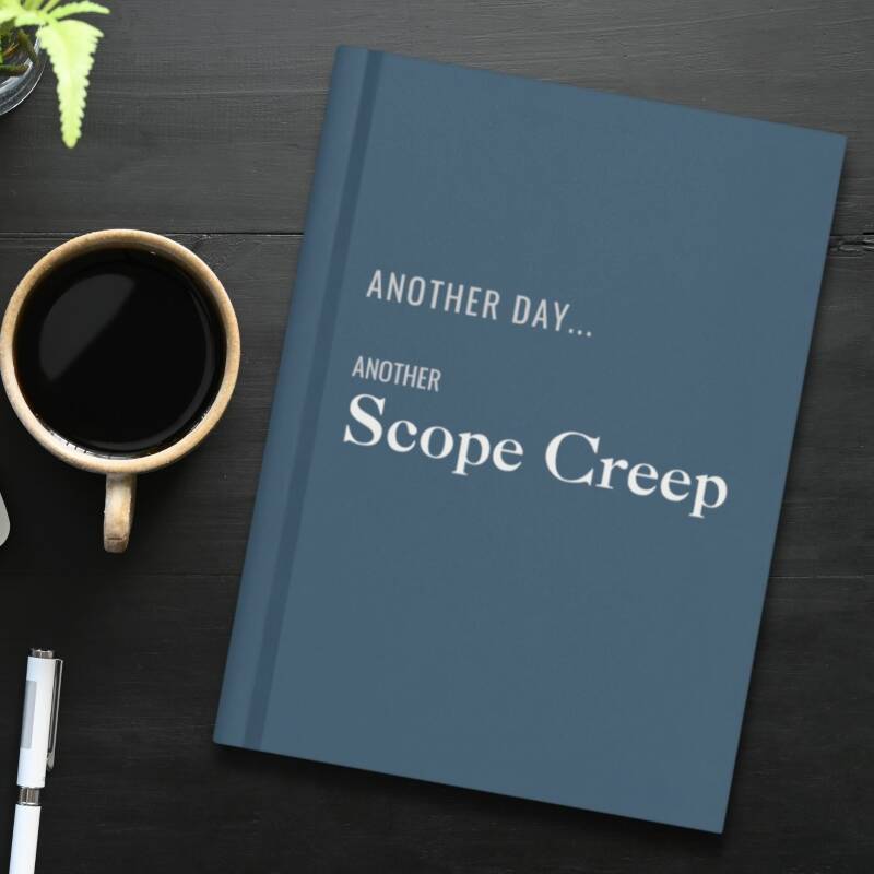 Slat blue hardcover lined journal on a desk with a cup of coffee and a pen.
