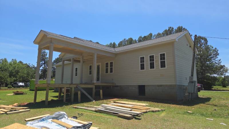 Outdoor space taking shape: the extended porch roof and raised wood platform show the layout of this residential project. / Un espacio exterior que toma forma: techo extendido y plataforma de madera elevada que muestran la distribución del proyecto.