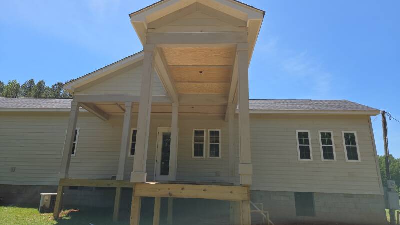 Covered porch details: a close view of the ceiling panels, beams and column trim during construction. / Detalles del porche techado: vista cercana de los paneles del cielo, las vigas y las molduras de las columnas durante la obra.