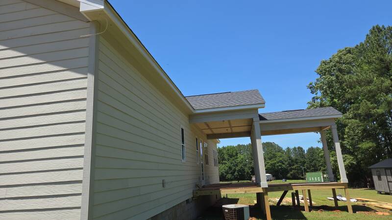 Attention to the details: this side view highlights the siding alignment, corner trim and connection between the home and covered porch. / Atención a los detalles: alineación del siding, molduras de esquina y unión de la casa con el porche.