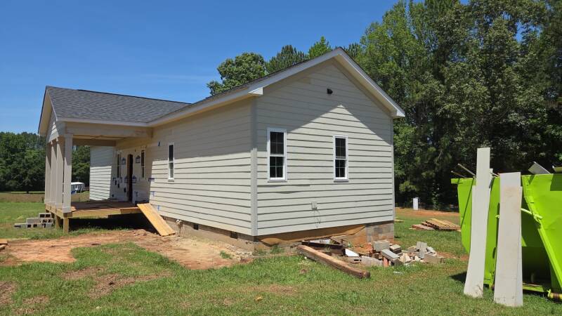 Exterior craftsmanship in Warrinton, NC: horizontal siding, window trim and a gable roof define this view of our project in progress. / Detalles exteriores: siding horizontal, molduras de ventanas y techo a dos aguas en esta obra en proceso.