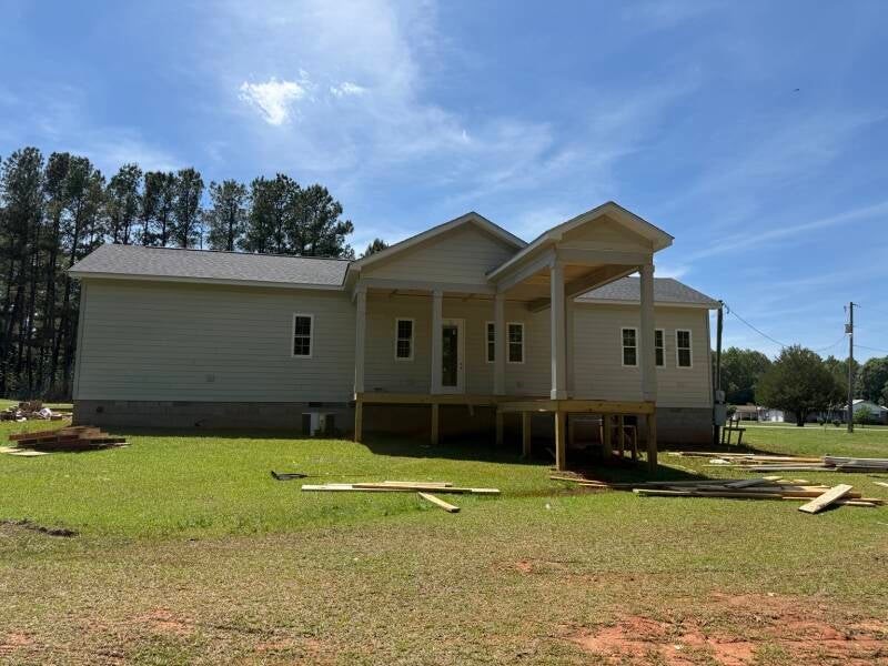 Project overview in Warrinton, NC: a wide view of the home, intersecting gables and covered porch as exterior work progresses. / Vista general del proyecto: vivienda, techos a dos aguas y porche cubierto durante el avance de los trabajos exteriores.