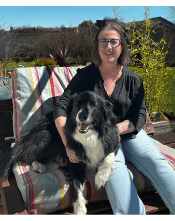 dame assise sur un canapé d'extérieur avec son border collie à coté d'elle un jardin et ciel bleu