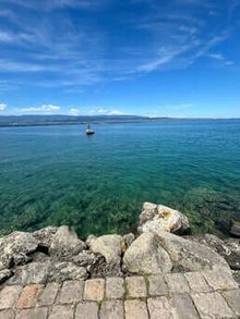 mer bleu turquoise avec ponton en pierre et un petit bateau au loin et la cote