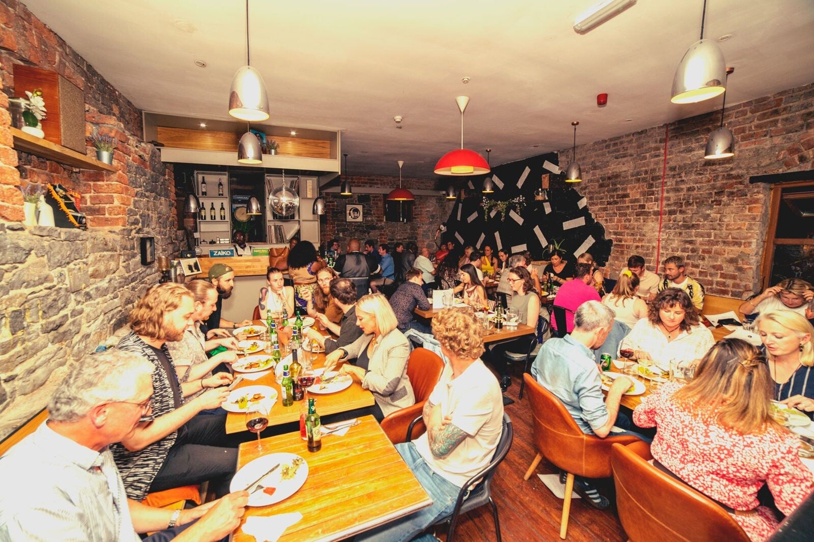 A packed party night at long tables under red lamps at Melody, Limerick