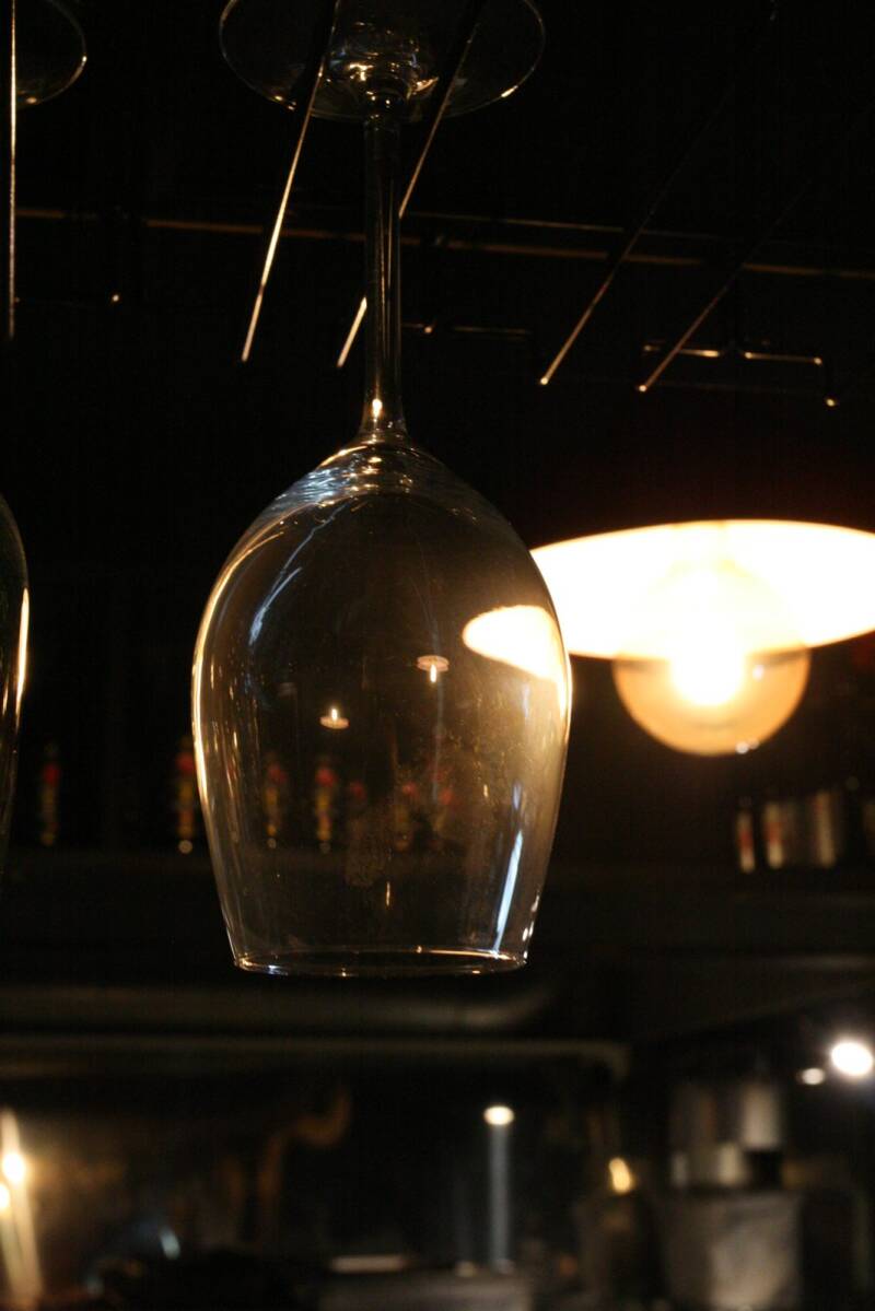 A wine glass hanging above the bar under warm lamplight at Melody, Limerick