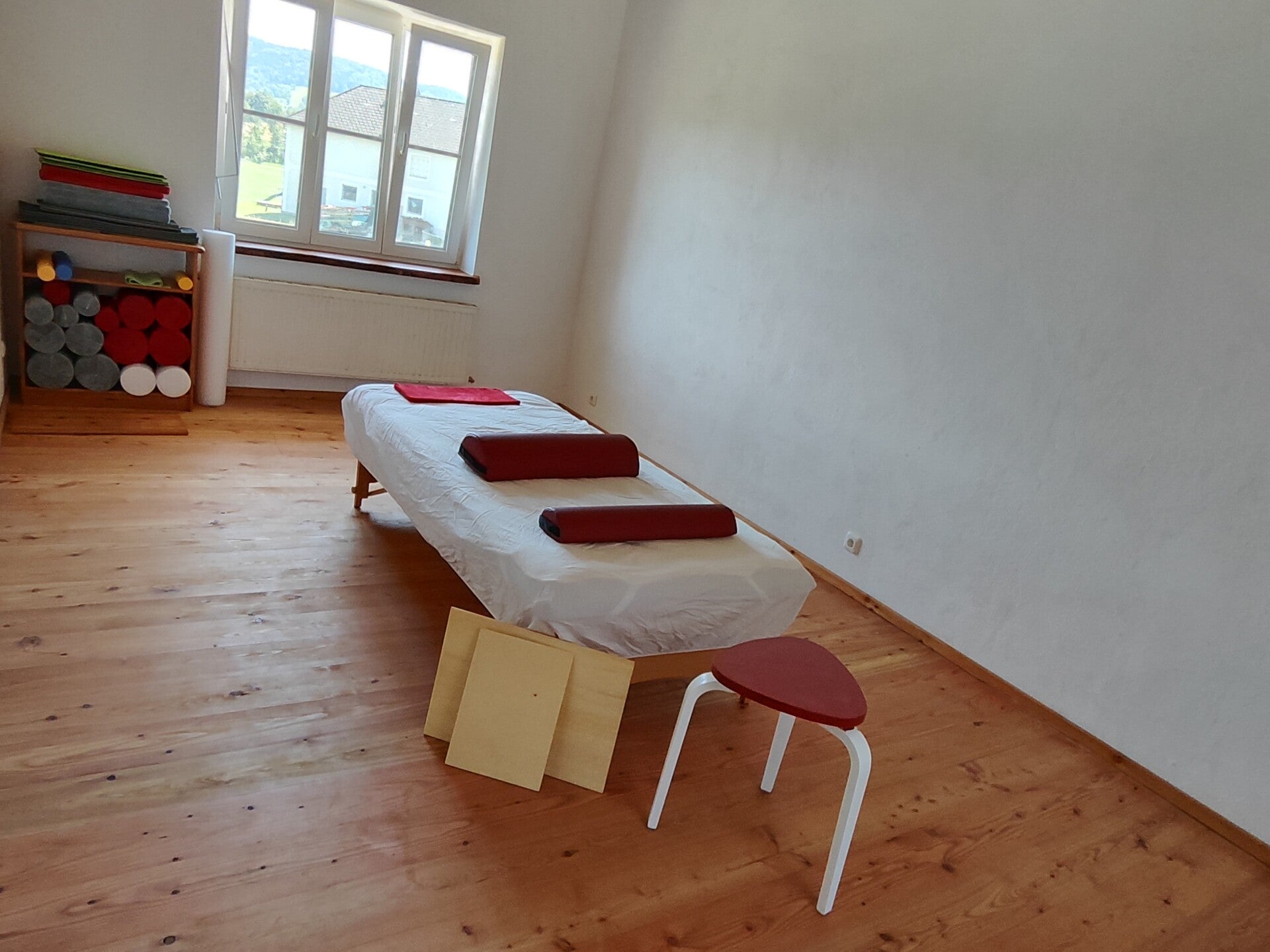 Bild einer funktionalen Integration bei der der Schüler auf der Feldenkrais Liege liegt während der Feldenkrais Lehrer mit sanften Berührungen seinen Körper bewegt um Bewusstsein und das Selbstbild zu stärken