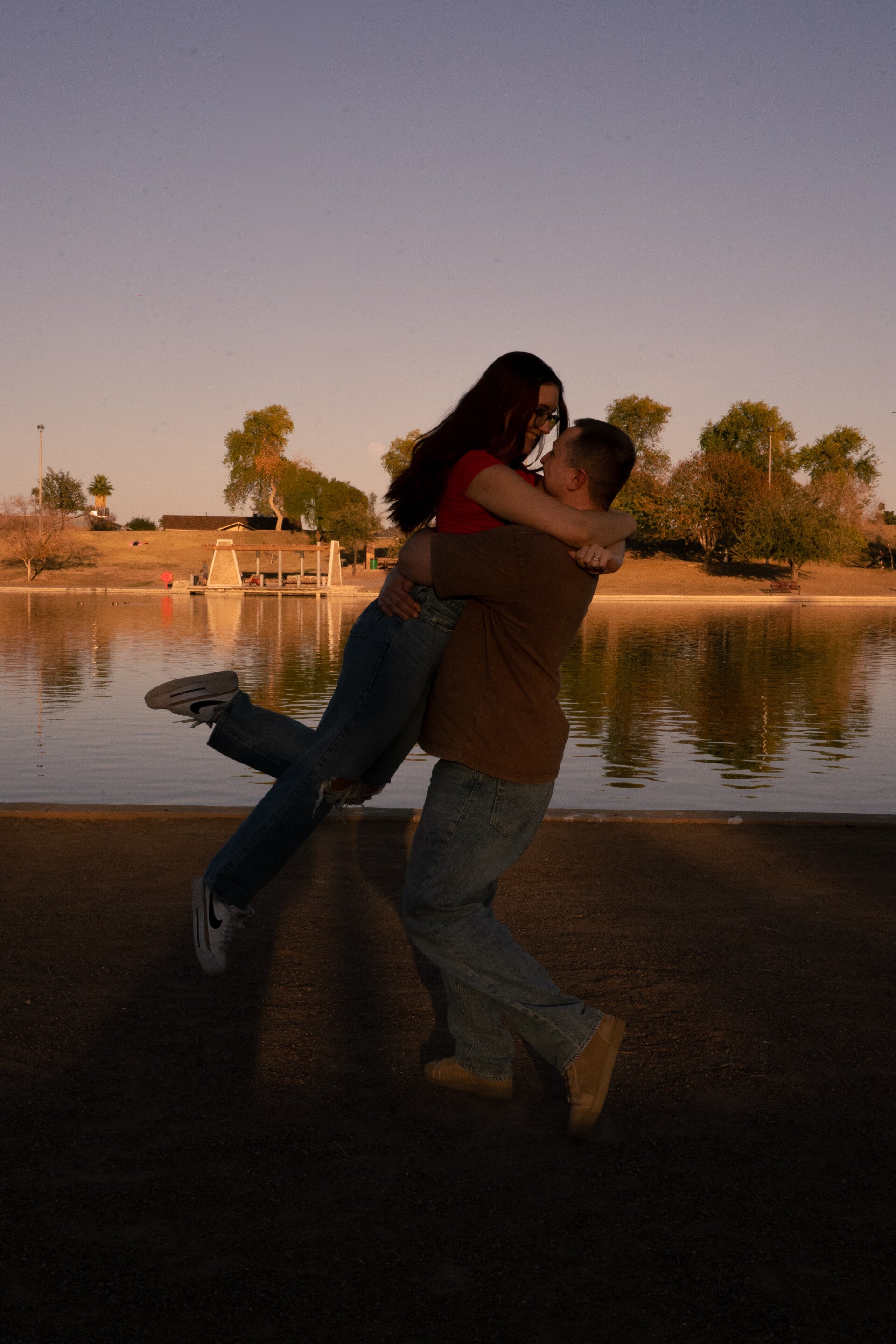 Girl jumping into husbands arms, being picked up with one leg bent and one leg straight