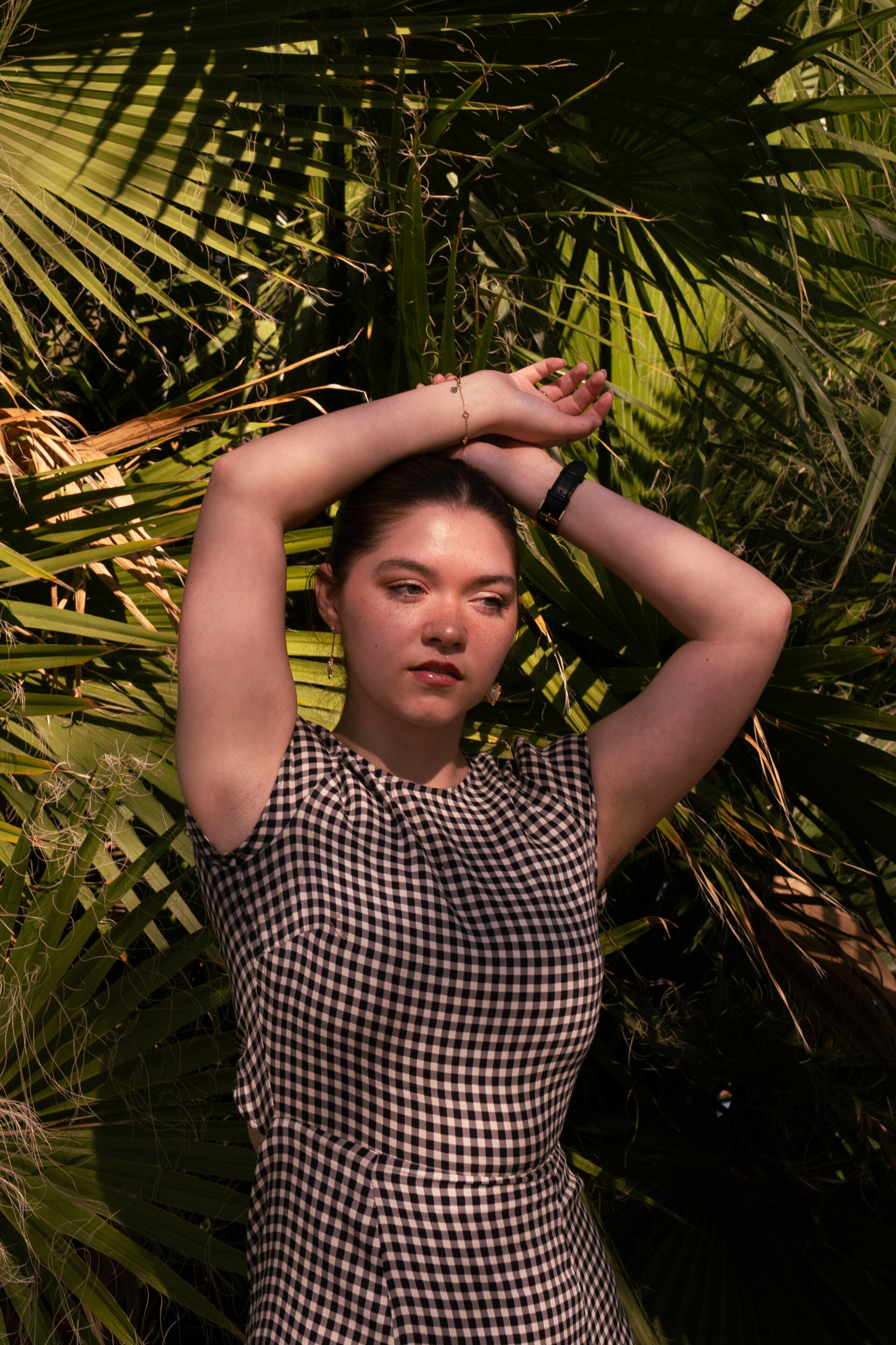 Model posing with arms up and wrists crossed over her head