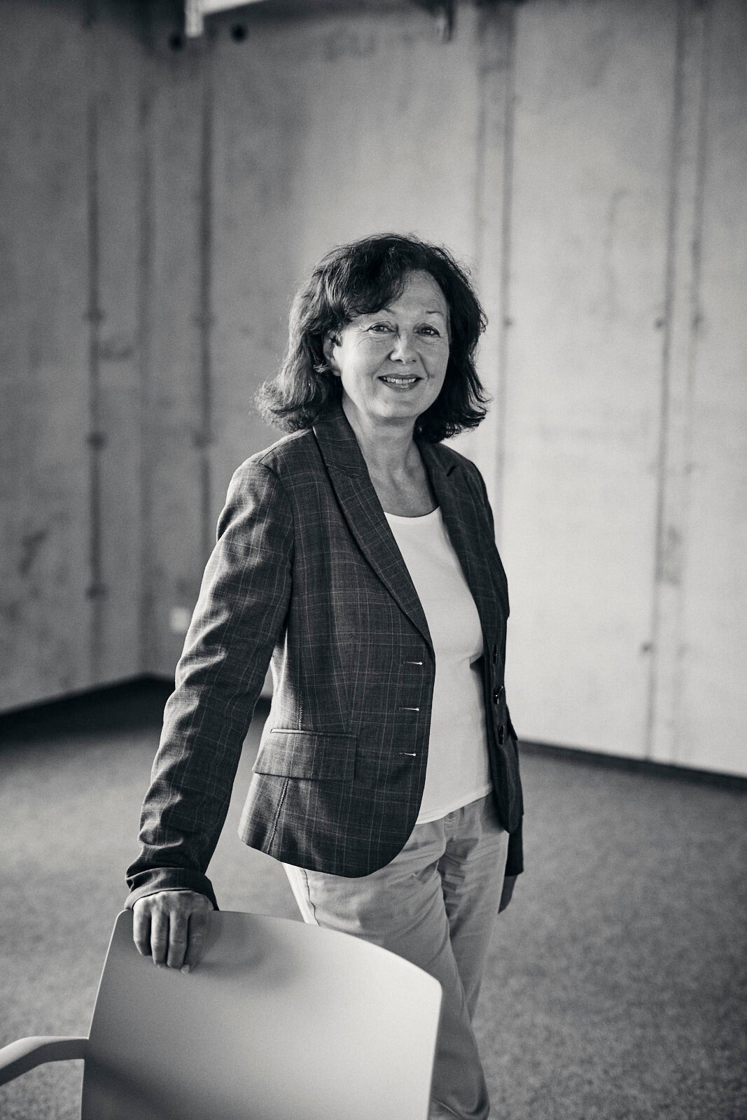 Auf dem Schwarz-Weiß-Bild ist die Inhaberin von b:serviced in einem weißen T-Shirt unter kariertem Blazer zu sehen. 