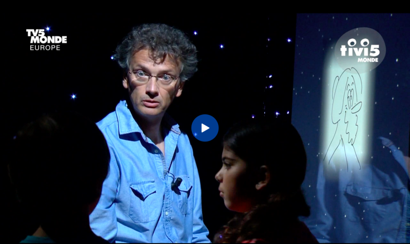 photo de Fiami qui dessine et raconte l'histoire des sciences à 2 enfants