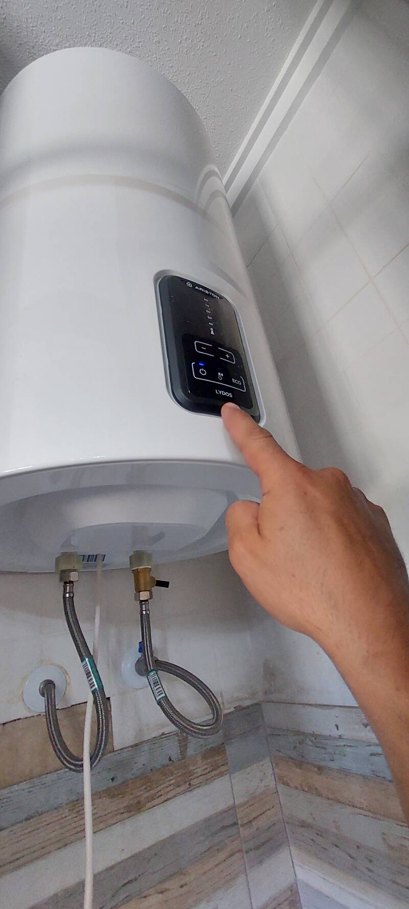 Technician adjusting temperature on an 80-liter Lydos water heater during emergency hot water repair and installation service in Torrevieja.