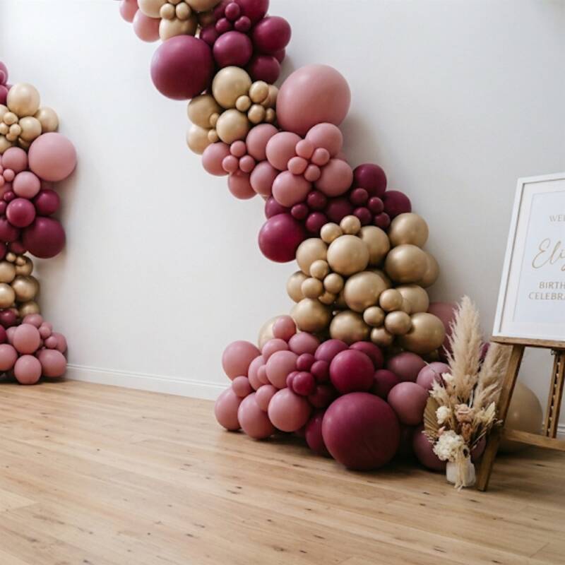 Organic balloon garland in dusty pink, burgundy and gold cascading down a wall
