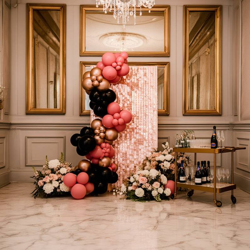 Rose gold sequin shimmer wall with a black, coral and gold balloon garland in an elegant ballroom