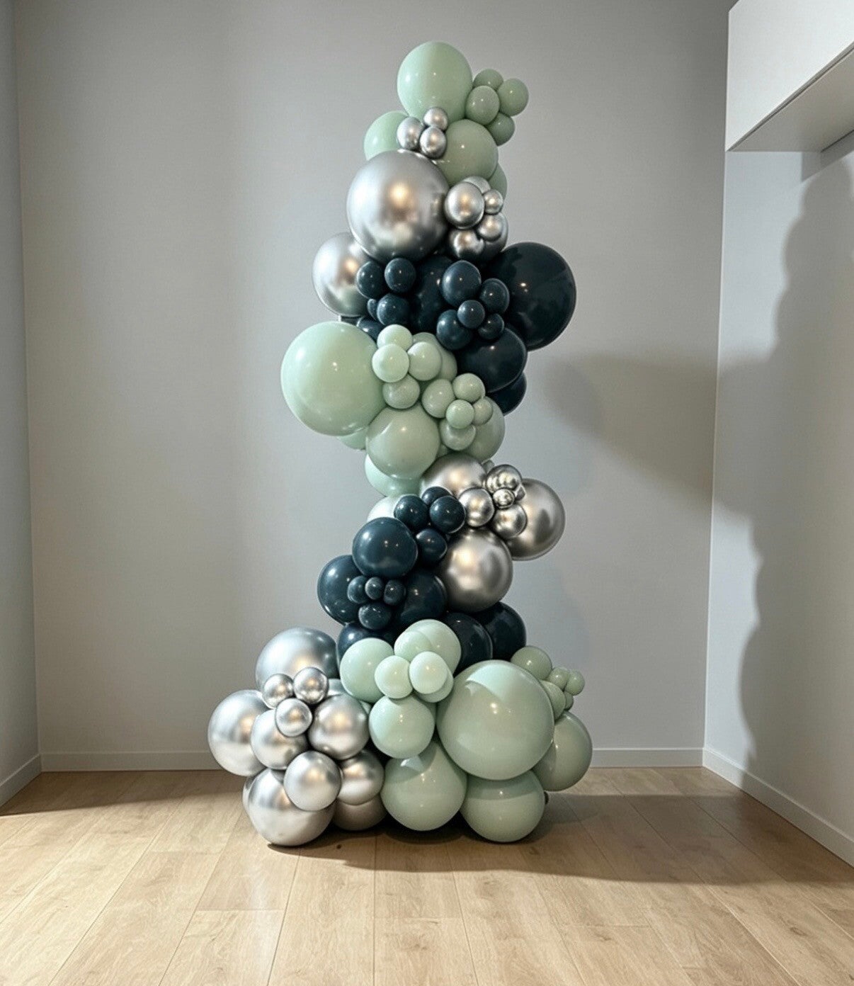 Tall organic balloon garland in mint green, navy and chrome silver styled in a bright room