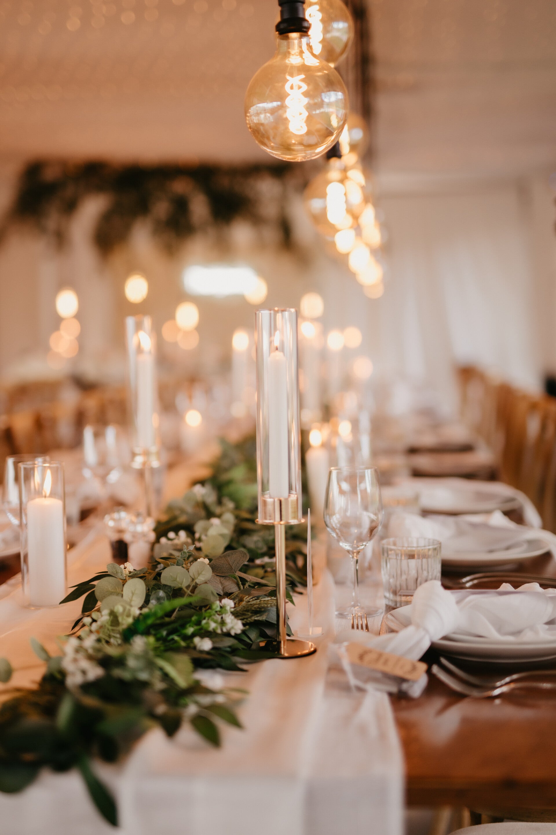 Long reception table with greenery runner, candles and place settings