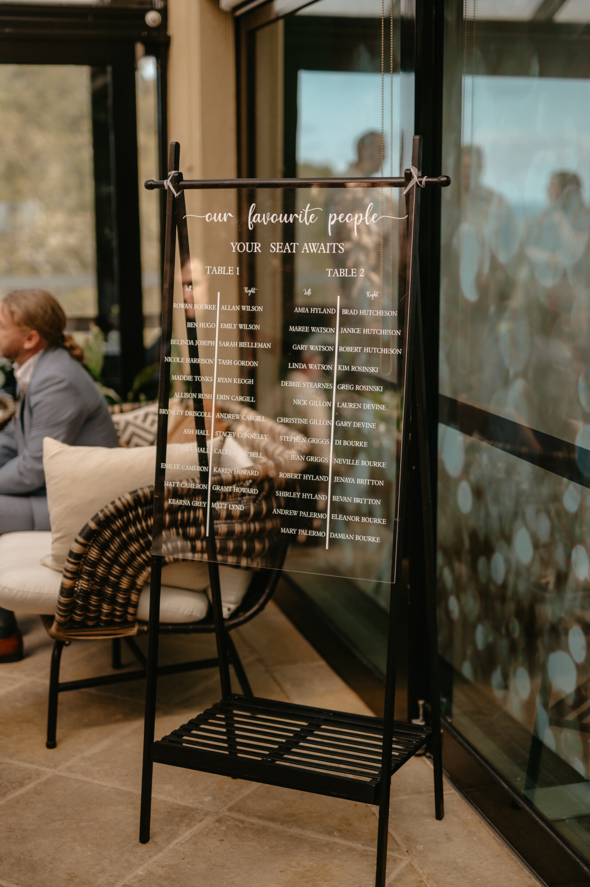 Glass seating chart sign displaying guest tables