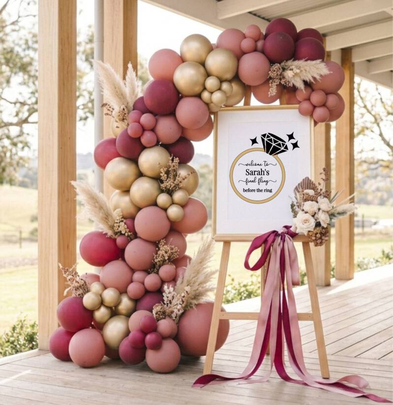 Dusty rose, burgundy and gold balloon garland arch with a Sarah's Final Fling Before The Ring hens party welcome sign