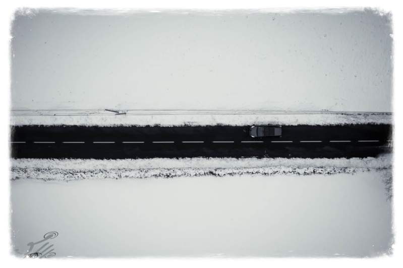 Vue aérienne artistique par drone au dessus de la neige dont le ruban noir de la  route traversante fait un beau contraste