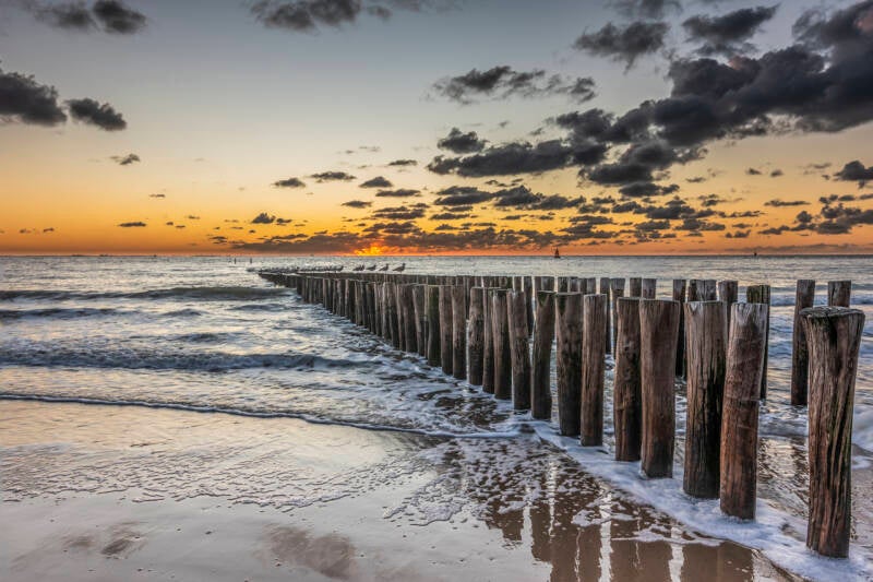 Zonsondergang golfbrekers strand Valkenisse