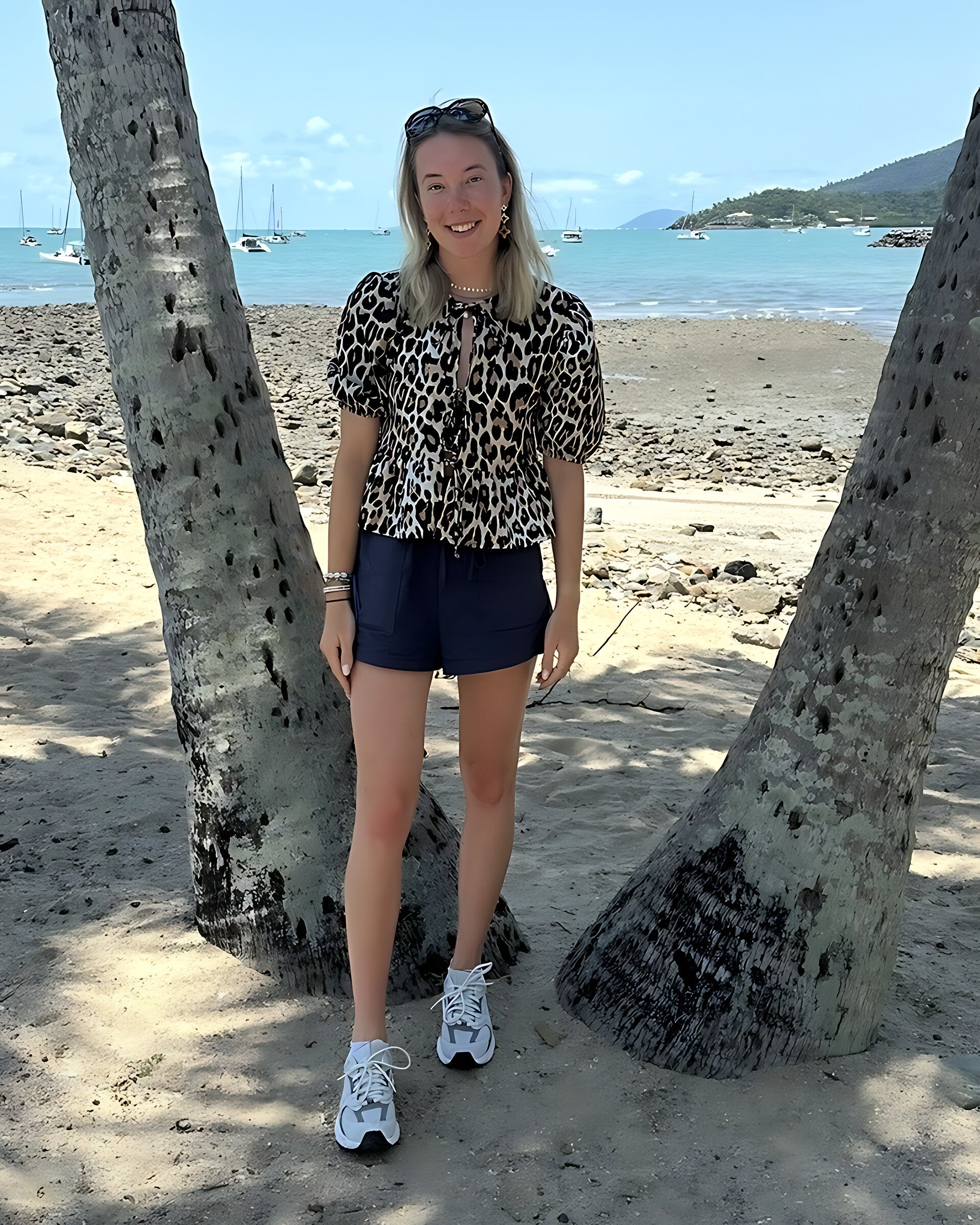 Romy, mede-eigenaar van ARTILUXE, tussen de palmbomen aan zee