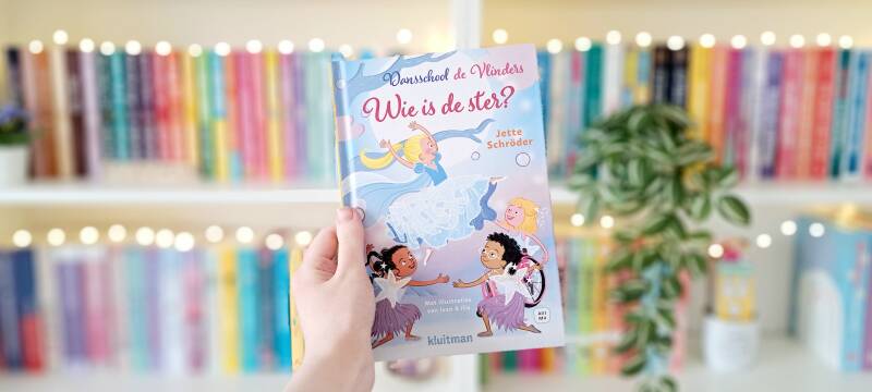 Een witte hand houdt 'Wie is de ster', deel drie van Dansschool de Vlinders van Jette Schröder en ivan en ilia. Recensie door Annemarie van turnthepages.nl