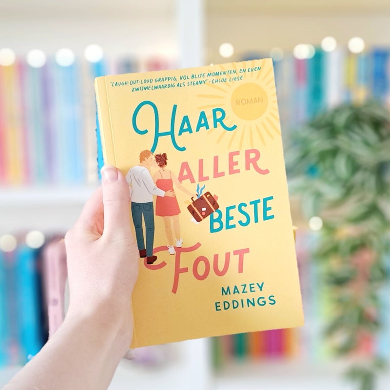 Een witte hand houdt 'Vis in een boom' van Lynda Mullaly Hunt omhoog voor een kleurrijke wazige boekenkast met lichtjes. Foto bij recensie door turnthepages.nl | Rolstoelgebruiker, disabled bookstagrammer en neurodivergente boekblogger.