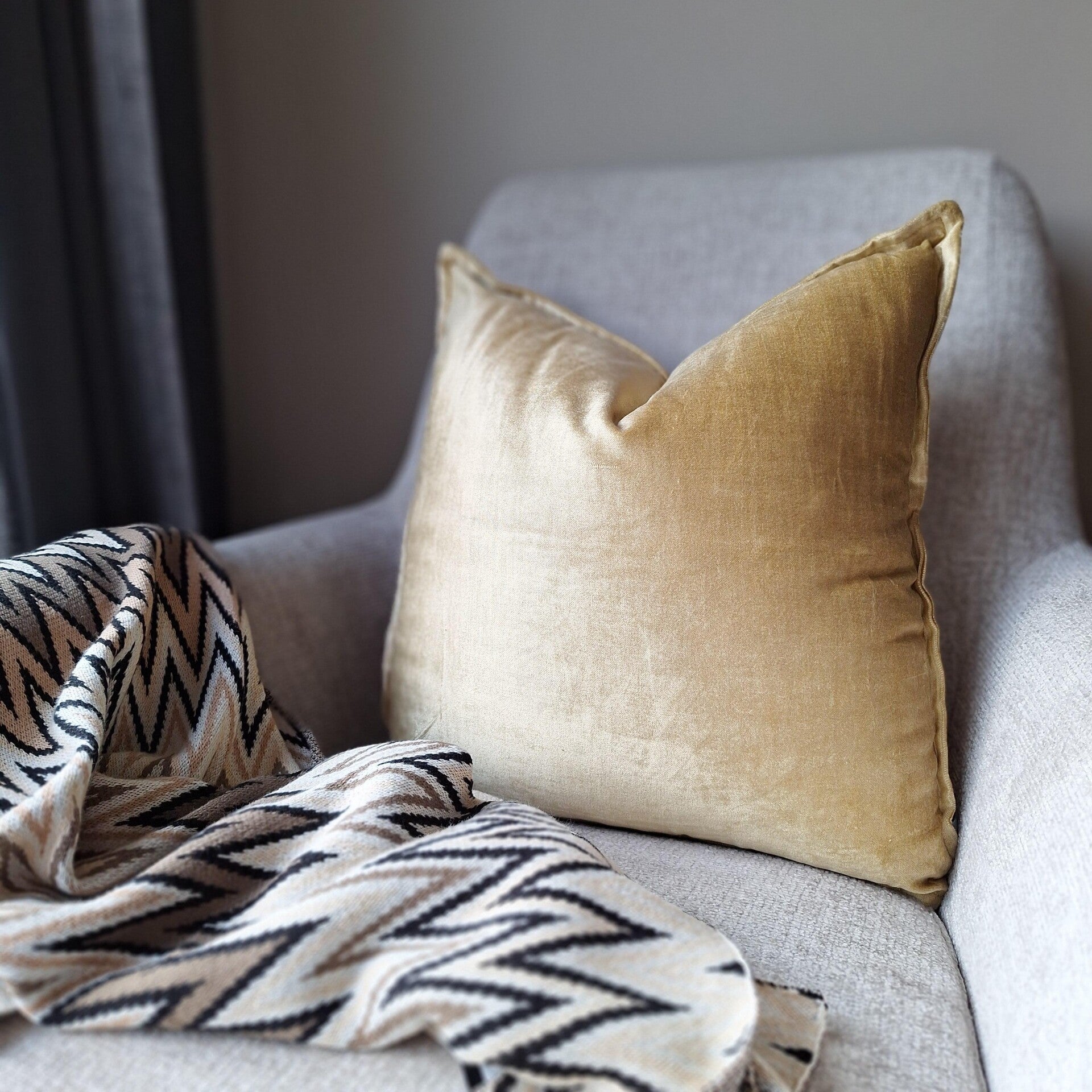 Luxe gouden sierkussen van Colmore op een fauteuil 