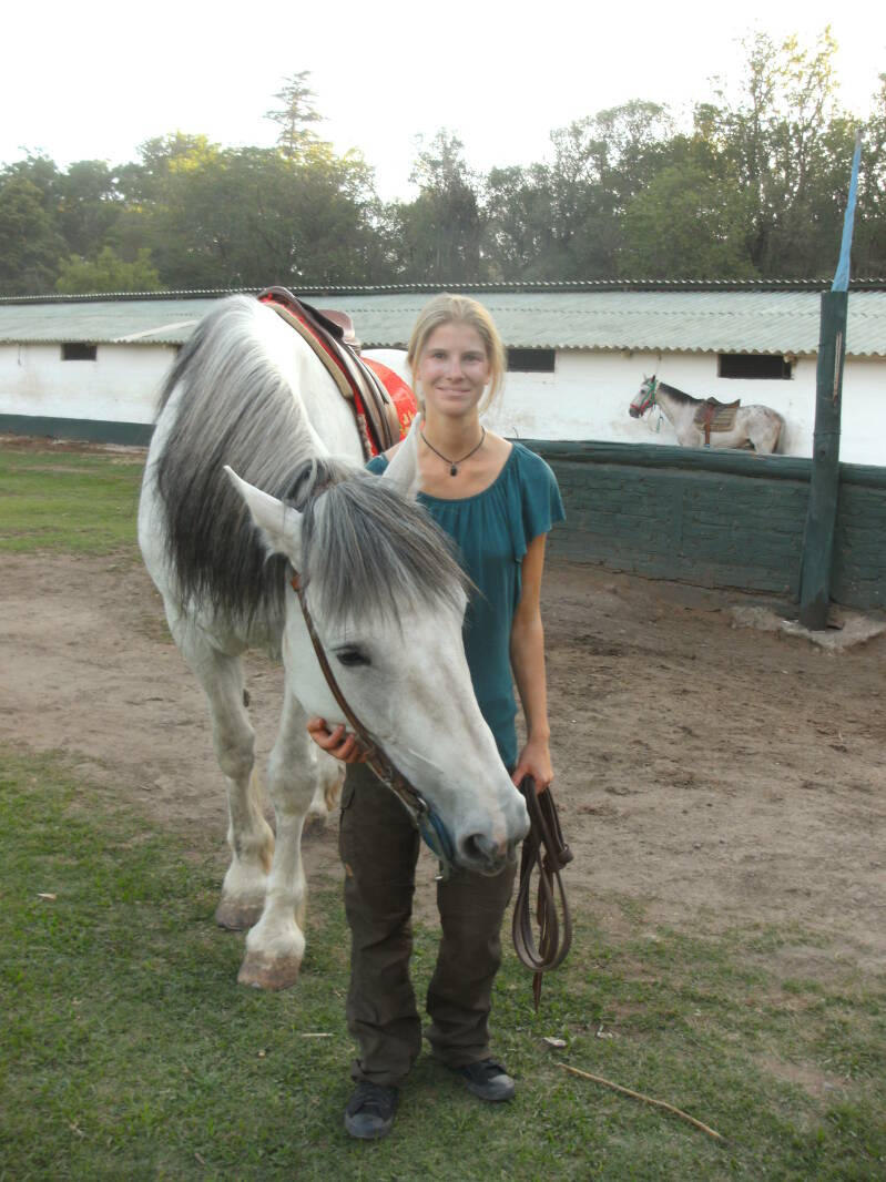 Reitlehrerin in Verbundenheit mit großem weißen Pferd neben sich