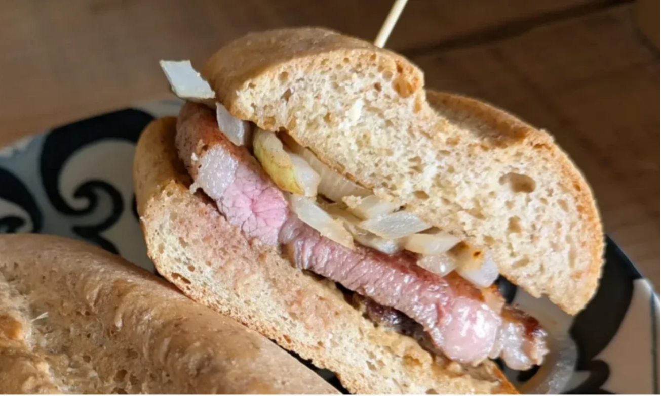 un bocadillo de churrasco de pasto con cebolla y mostaza francesa