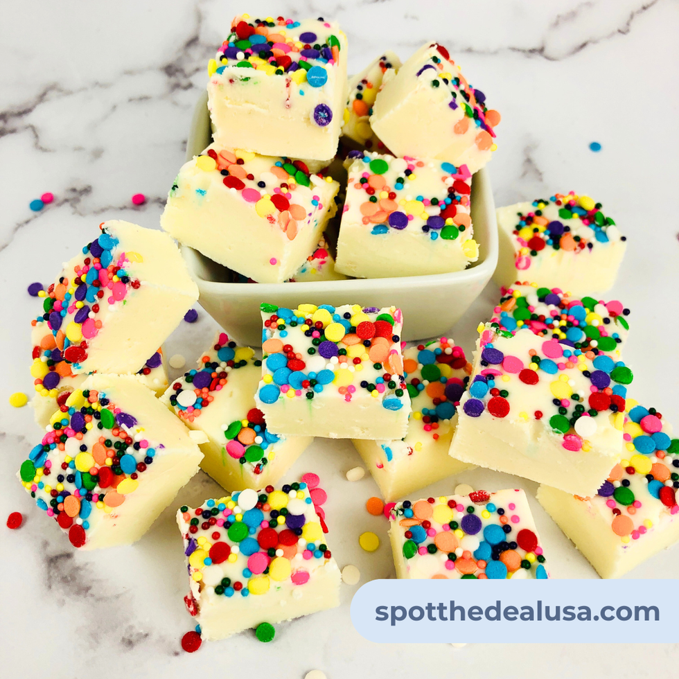 White chocolate sugar cookie fudge topped with colorful sprinkles, cut into squares and served on a plate.