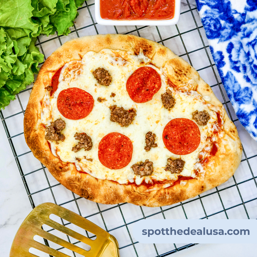 Cheesy flatbread pizza on a Blackstone griddle with crispy naan crust, melted cheese, and sizzling sausage and pepperoni.
