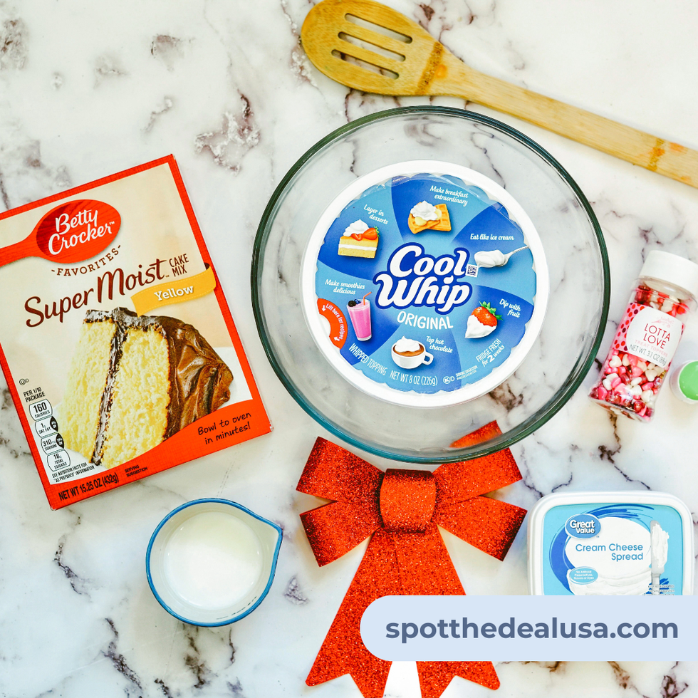 A variety of ingredients including a box of cake mix, cool whip, sprinkles and cream cheese spread.