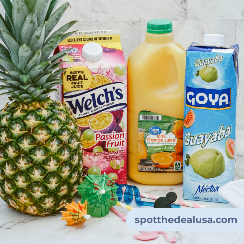 Bottles of guava, orange, and passion fruit juice arranged on a countertop next to a bowl of ice cubes and fresh oranges for garnish.
