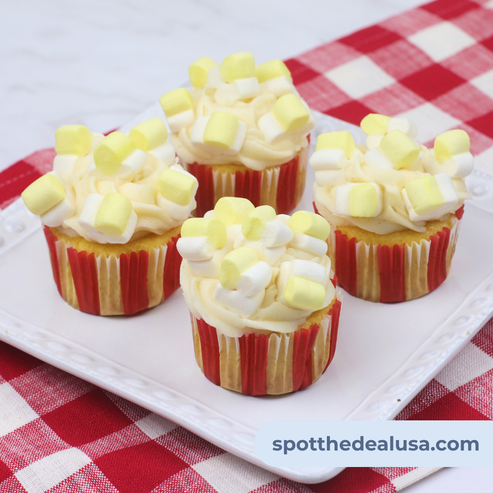 Yellow cupcakes topped with swirled browned butter frosting and popcorn-shaped marshmallows, served in colorful liners for a carnival-themed dessert.