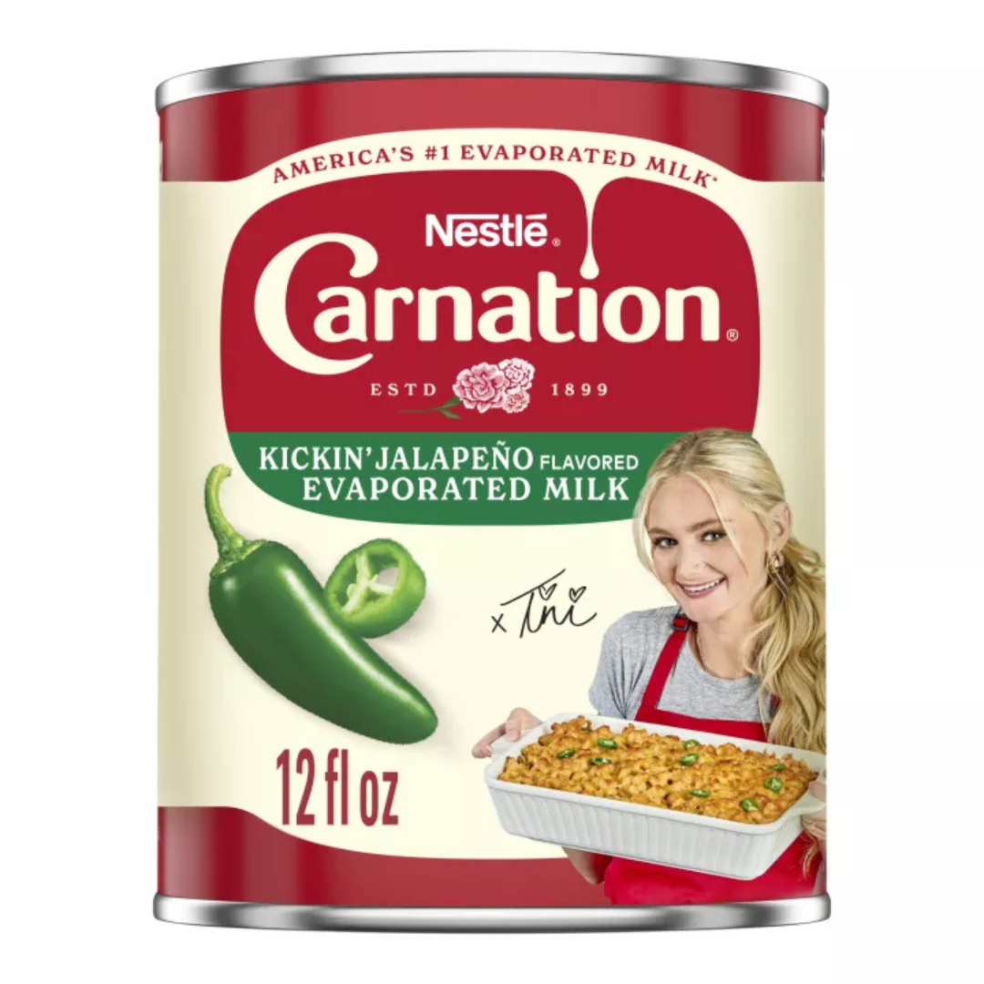 A 12 oz can of Carnation Kickin’ Jalapeño Flavored Evaporated Milk next to a spicy baked mac and cheese dish on a kitchen counter.