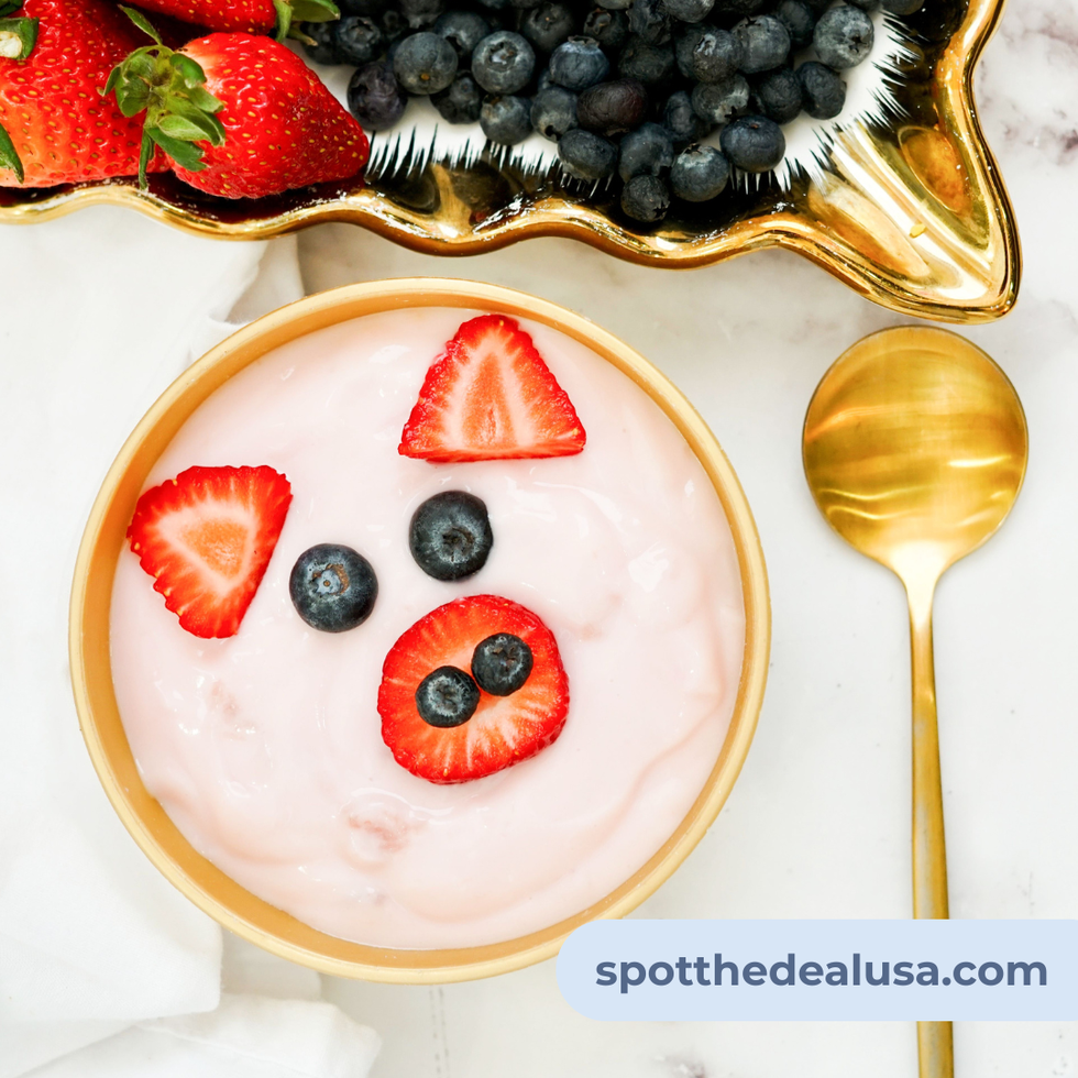 Piggy face yogurt bowl made with strawberry yogurt, strawberry slices and blueberries.