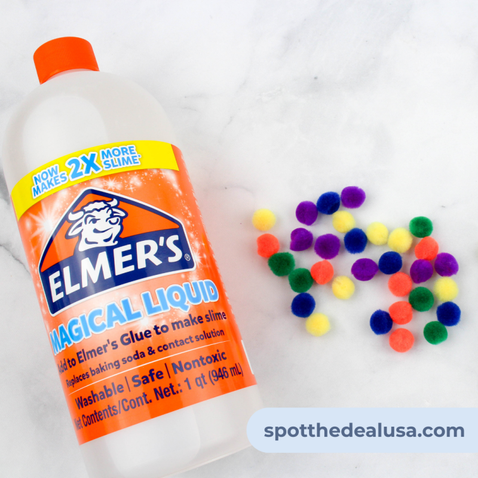 Clear slime with colorful pom poms displayed next to a bottle of Elmer’s Magical Liquid on a flat surface.
