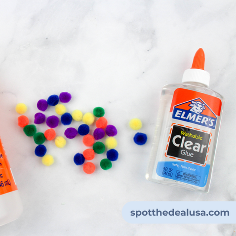 Finished pom pom slime sitting beside a bottle of Elmer’s Clear Glue.