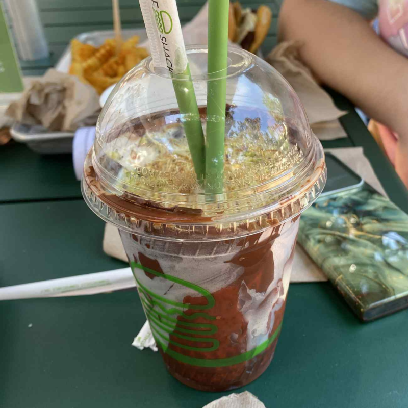 Shake Shack Chocolate Pistachio Shake on a table, topped with chopped pistachios and crunchy kataifi.