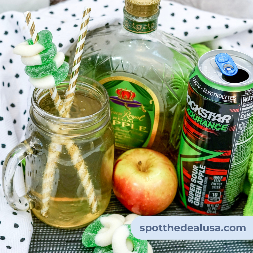 Sparkling sour apple whiskey cocktail served over ice and garnished with green apple candy rings in a clear glass.