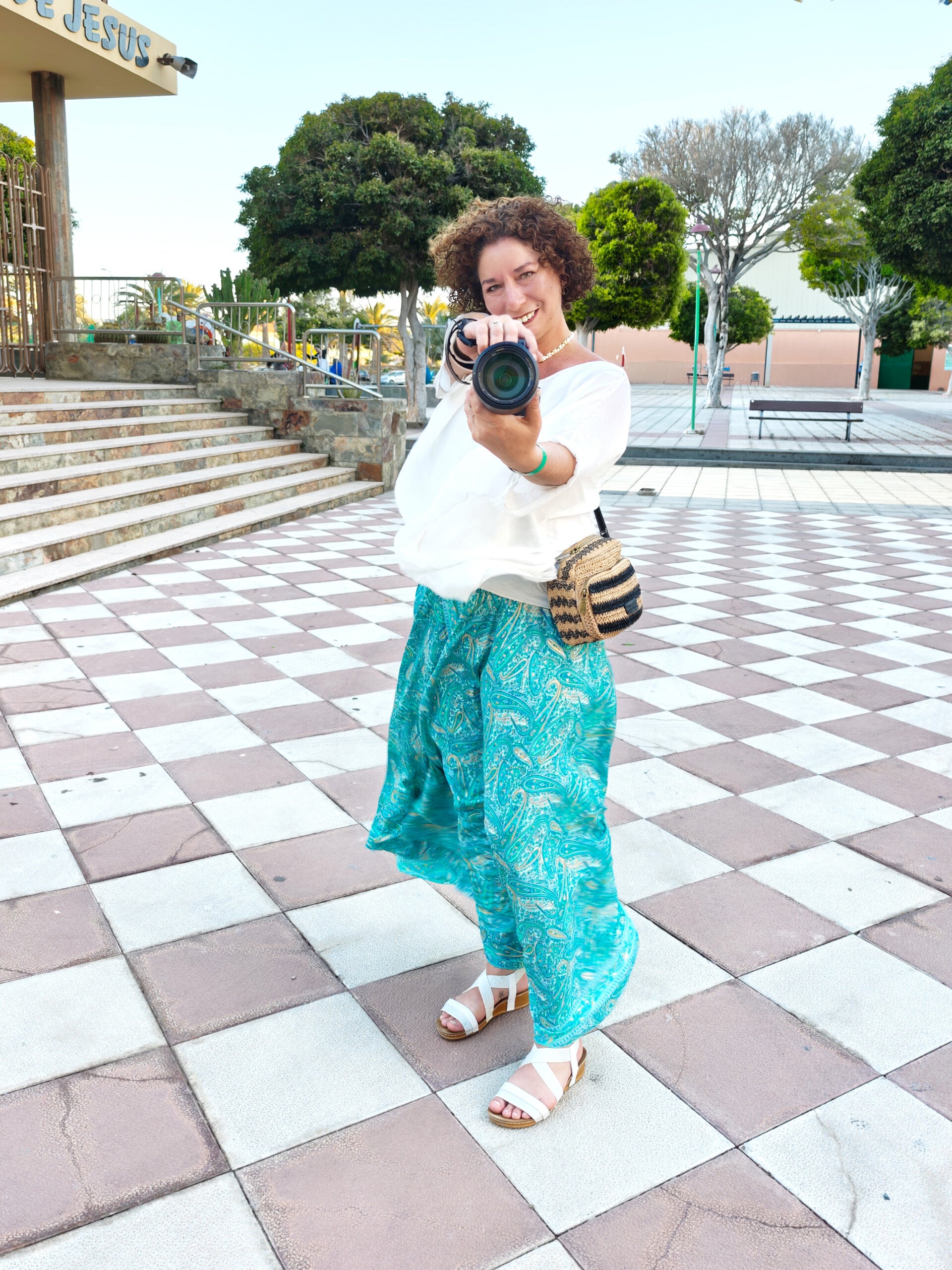 Fotografin Patricia Villafana Moya, Inhaberin von FOTO Villa in Germering, hat eine Kamera in der Hand und blickt glücklich in eine andere Kamera.