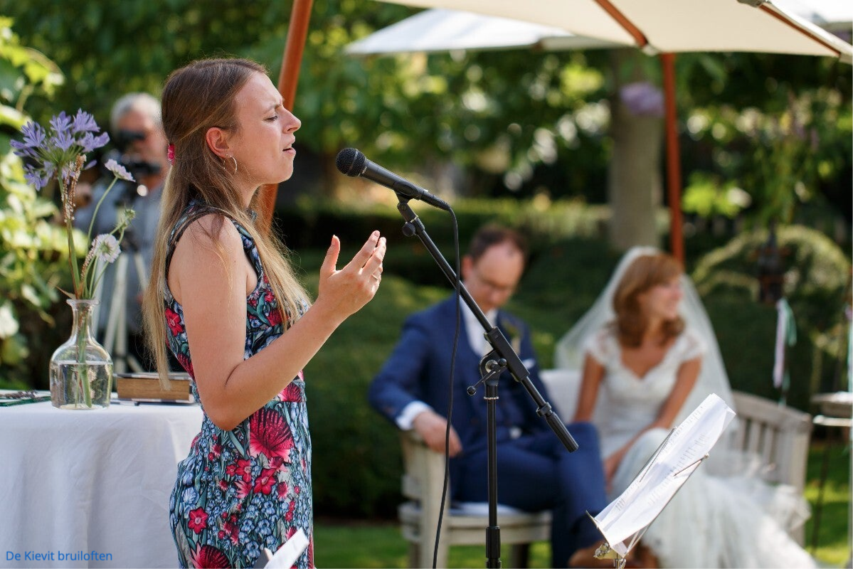 Bruiloftzangeres Noël van de Wiel zingend op bruiloftceremonie met bruidspaar op achtergrond