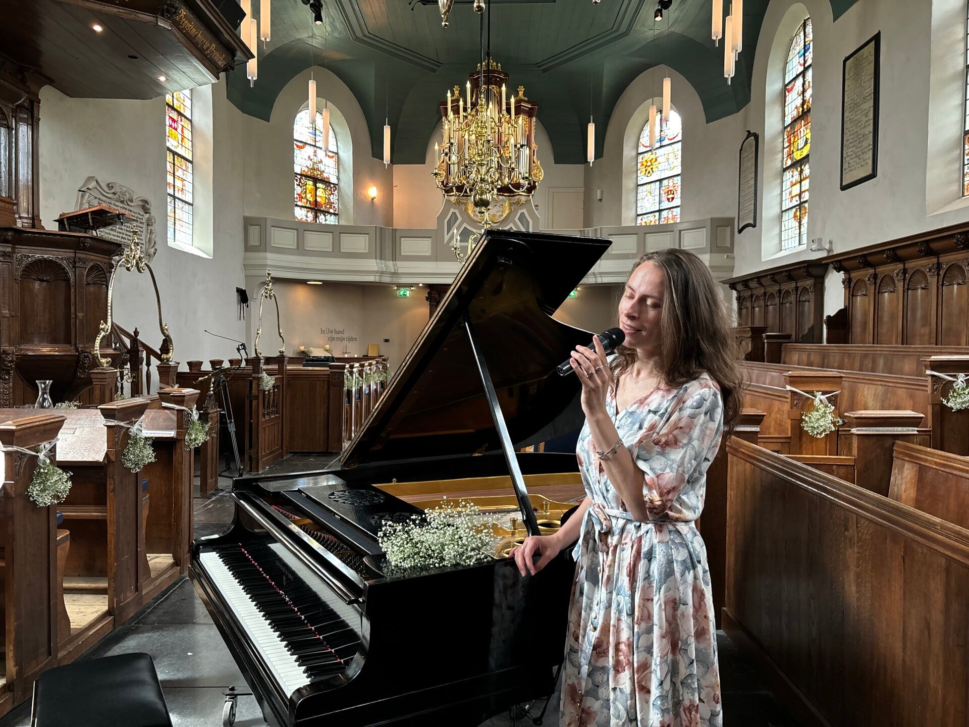 Zangeres Noel zingend voor zwarte vleugel in een kerk tijdens een huwelijksceremonie