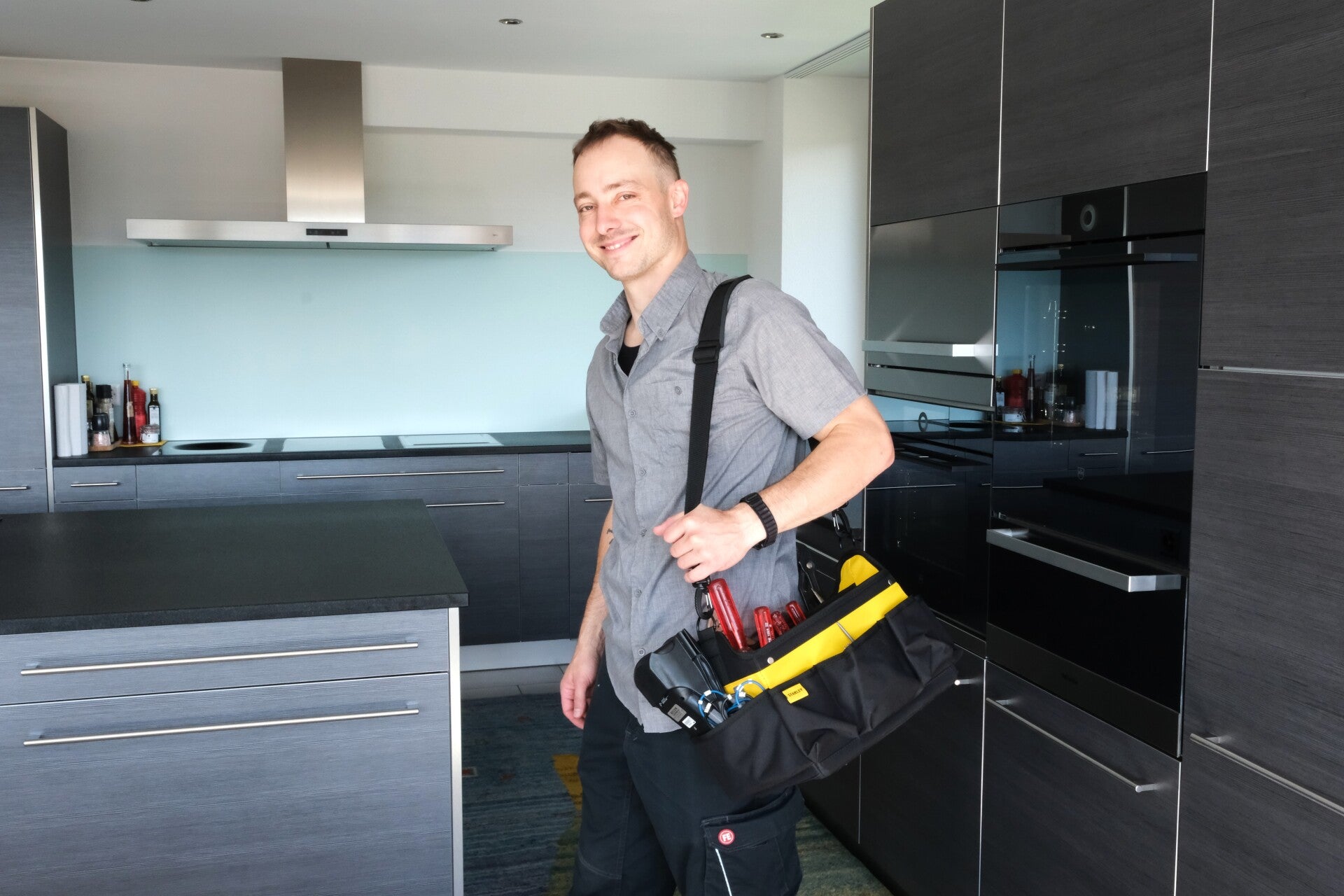 Einsatzbereiter Servicetechniker mit Werkzeugtasche für Reparatur- und Maintenance-Arbeiten vor Ort.