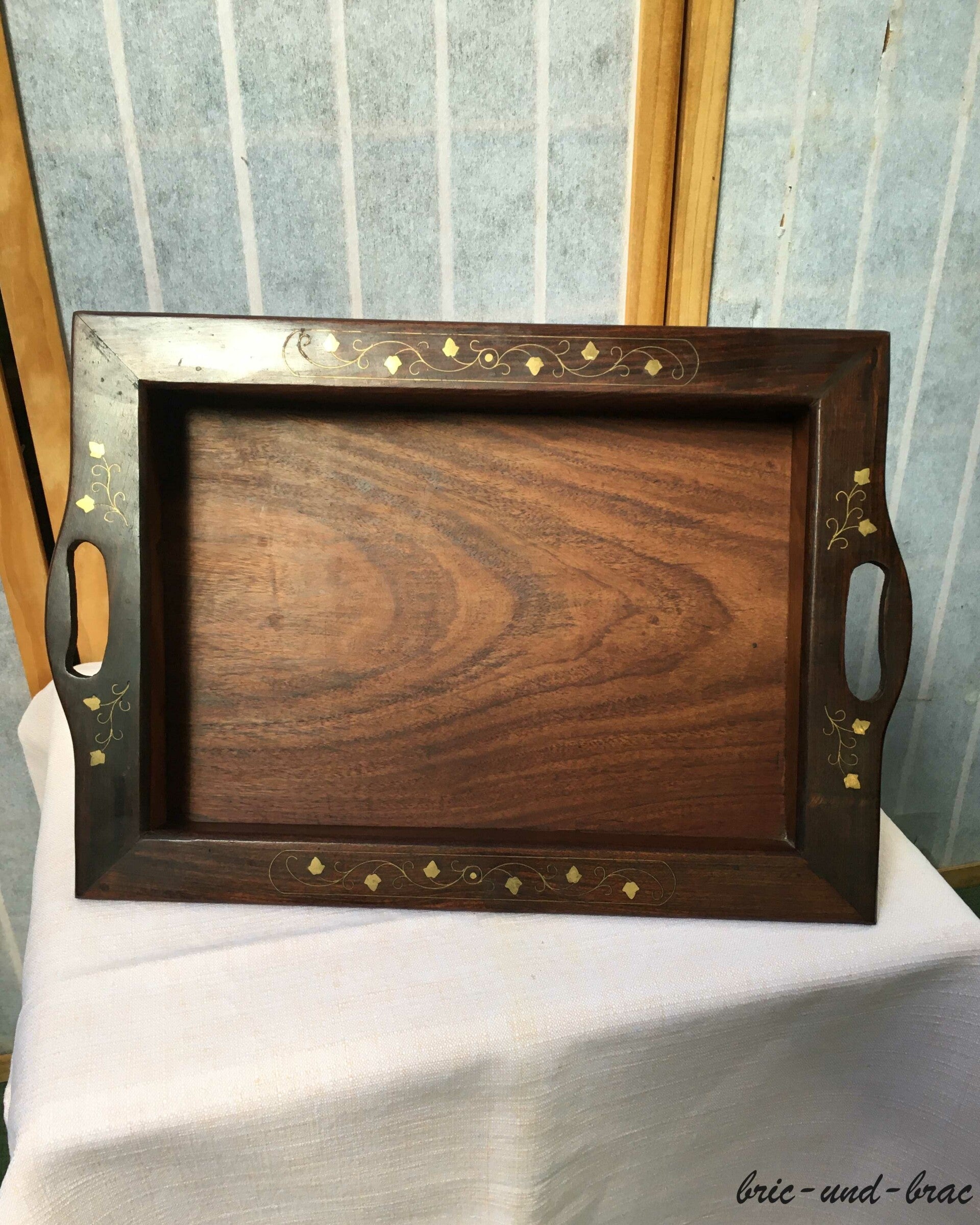 Es besitzt einen erhöhten, überstehenden Rand, in welchem an den Längsseiten die Griffe ausgenommen wurden. Die Intarsien sind in Blattform und vollständig erhalten