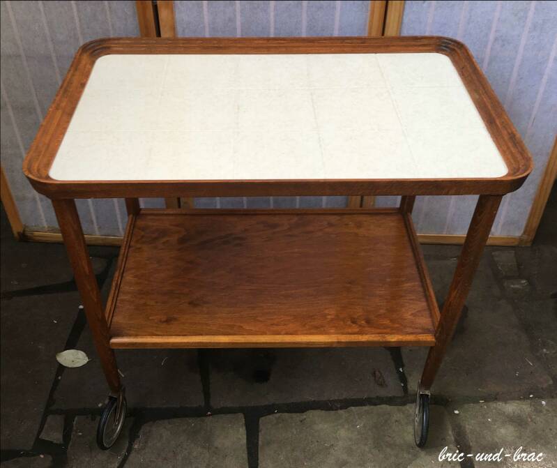 Klassischer Servier-/ Beistellwagen in Nussbaum oder nussbaum gebeizt mit zwei Etagen. Er hat vier drehbare Rollen, die einwandfrei funktionieren und auch noch intakte Gummierung haben. Die obere Platte ist durchgehend aus Keramik mit Fliesenstruktur.