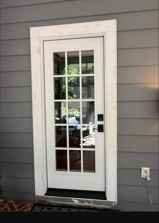 White 15-lite glass exterior door with black hardware on a siding home