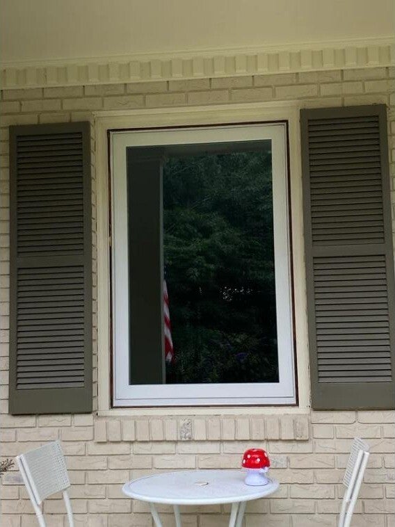 Replacement window with shutters on a brick home, viewed from the patio